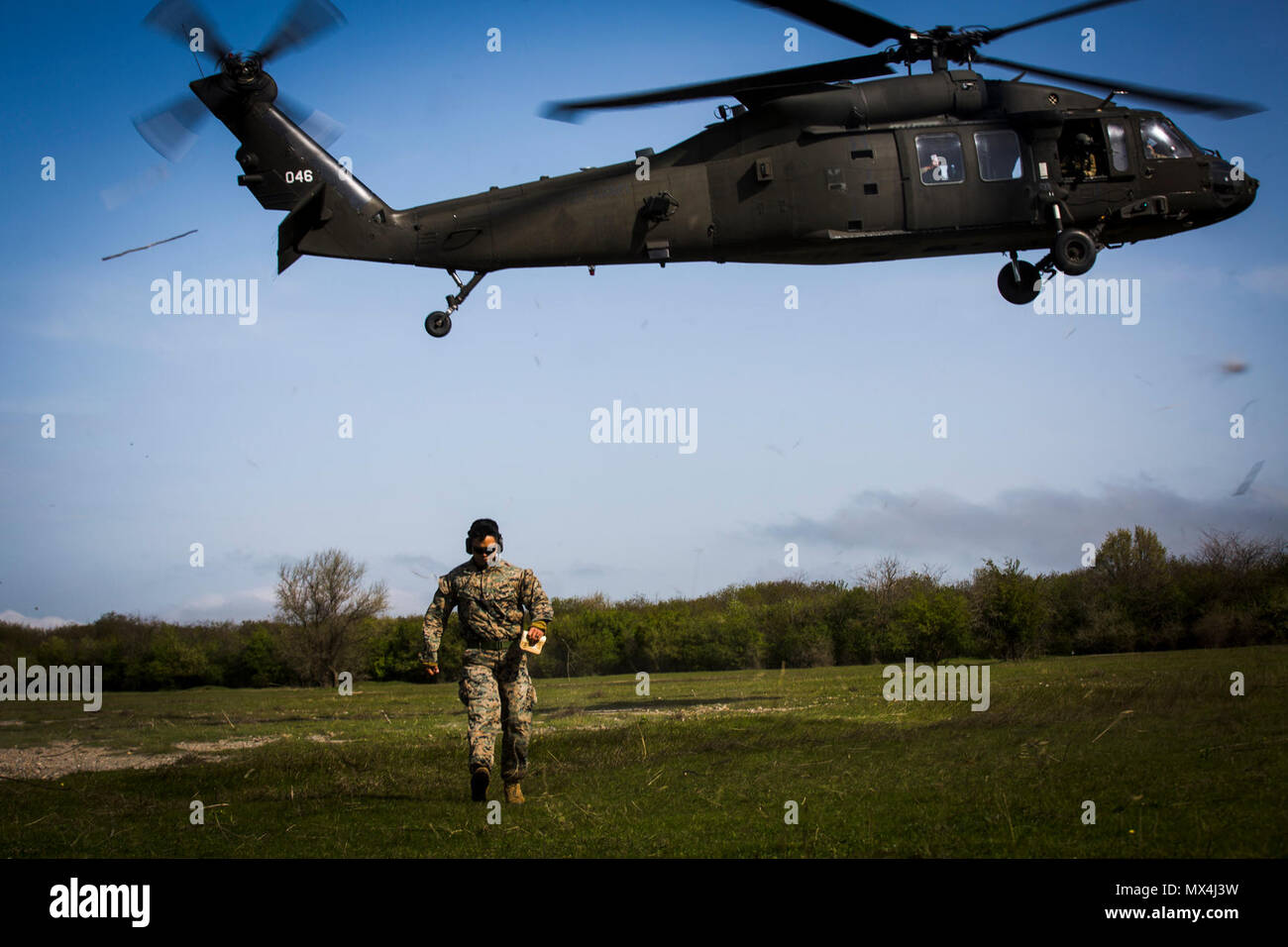 U.S. Marine Sgt. Viktor Cadiente, a forward observer with Black Sea Rotational Force 17.1, calls in the landing of a U.S. Army UH-60 Blackhawk helicopter during Exercise Platinum Eagle 17.2 at Babadag Training Area, Romania, April 30, 2017. Marines with BSRF and Marine Rotational Force Europe 17.1 held a class with Montenegrin soldiers over landing helicopters for casualty evacuations to improve on skills and interoperability. Partnerships formed from multinational exercises like this, and military-to-military training engagements are crucial in dealing with regional issues and keeping peace i Stock Photo