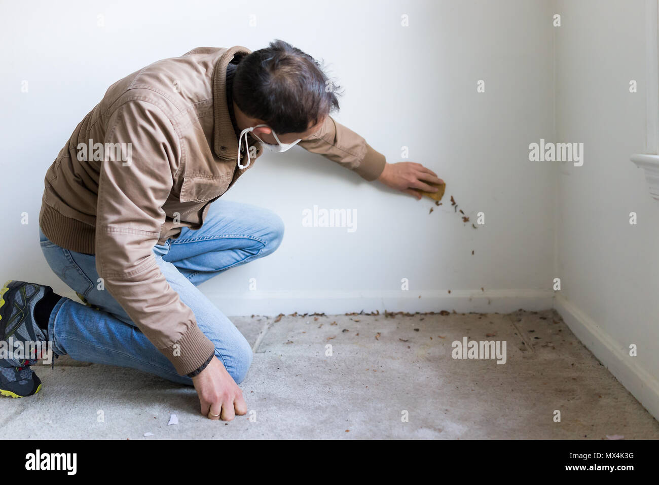 Young Man In Mask Sitting Crouching By Room Wall Carpet Floor
