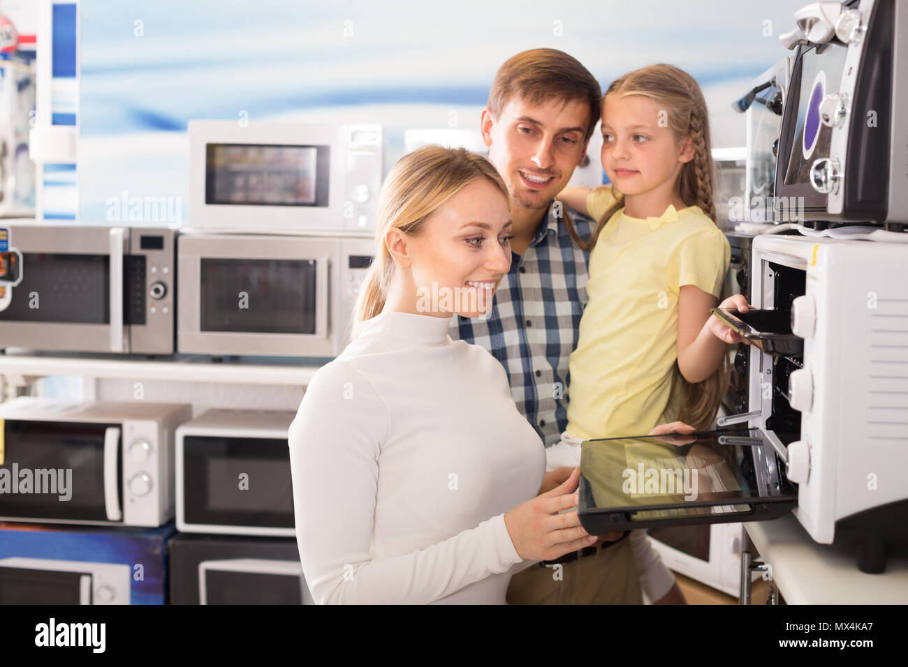 Portrait of positive family choosing microwave oven in hypermarket Stock Photo