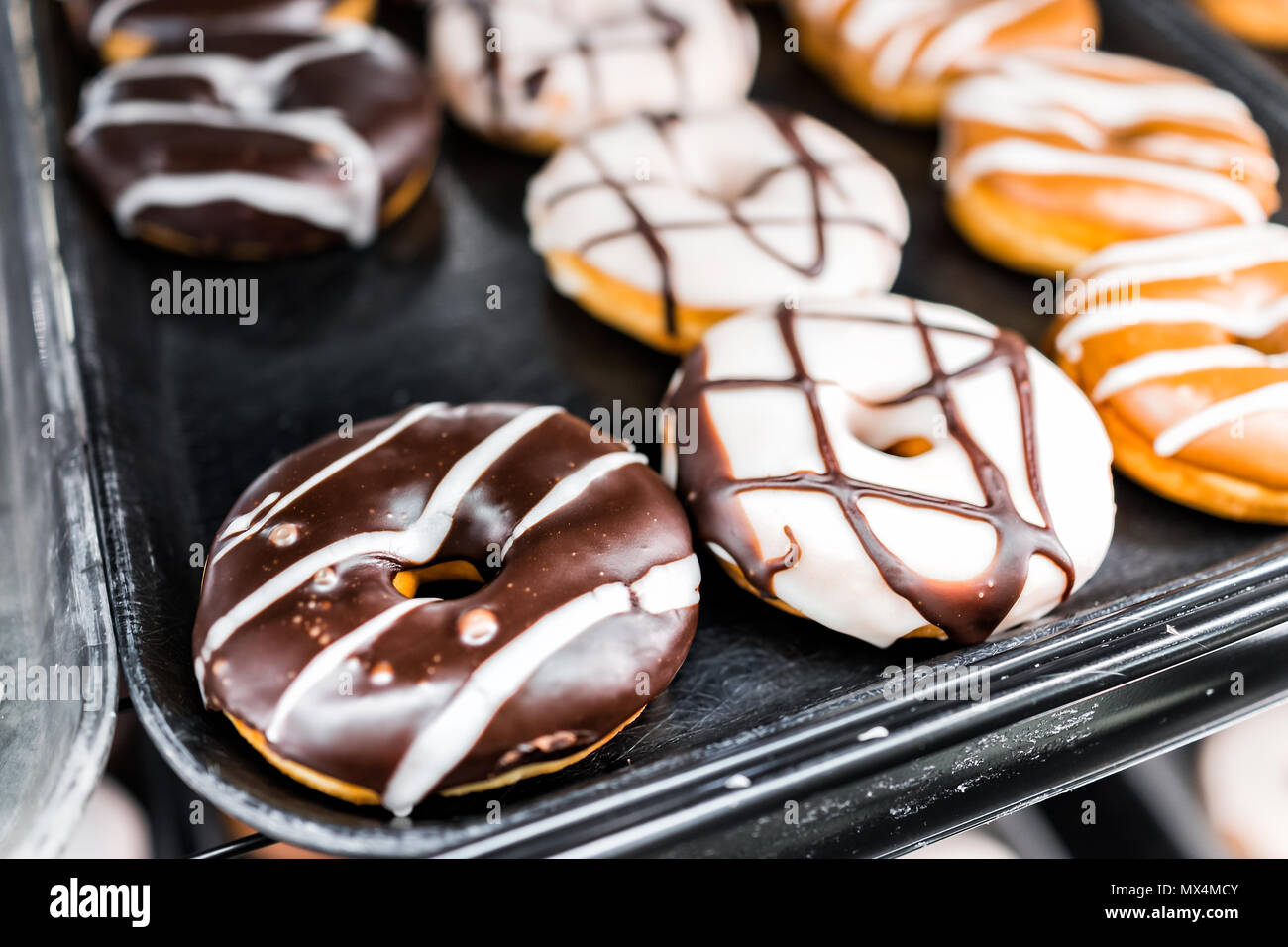 Chocolate brown and white icing donuts with holes closeup on bakery ...