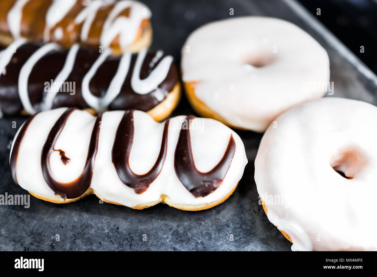 Chocolate brown and white icing long john donuts closeup on bakery tray ...