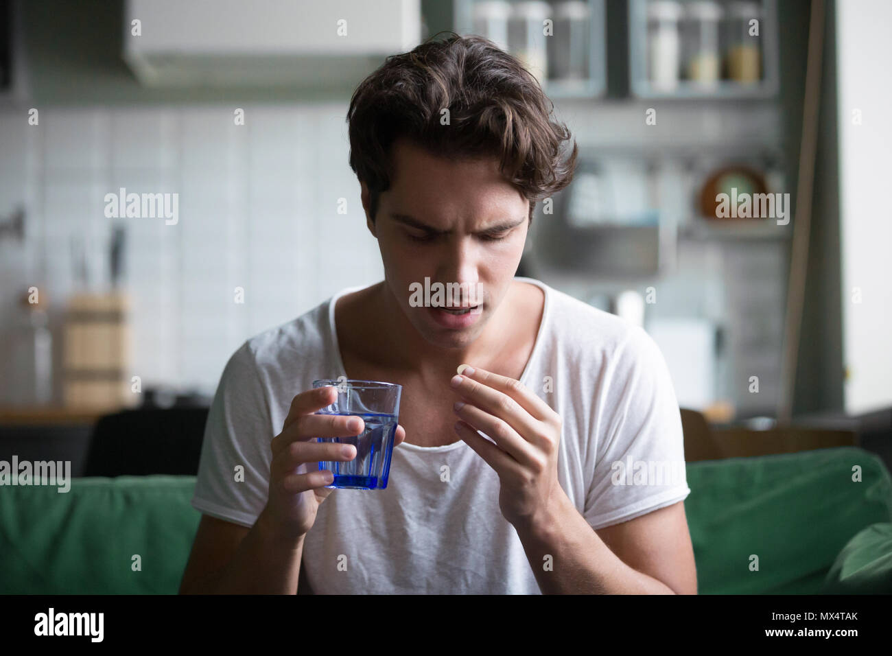 Millennial man taking pill to relieve pain at home Stock Photo