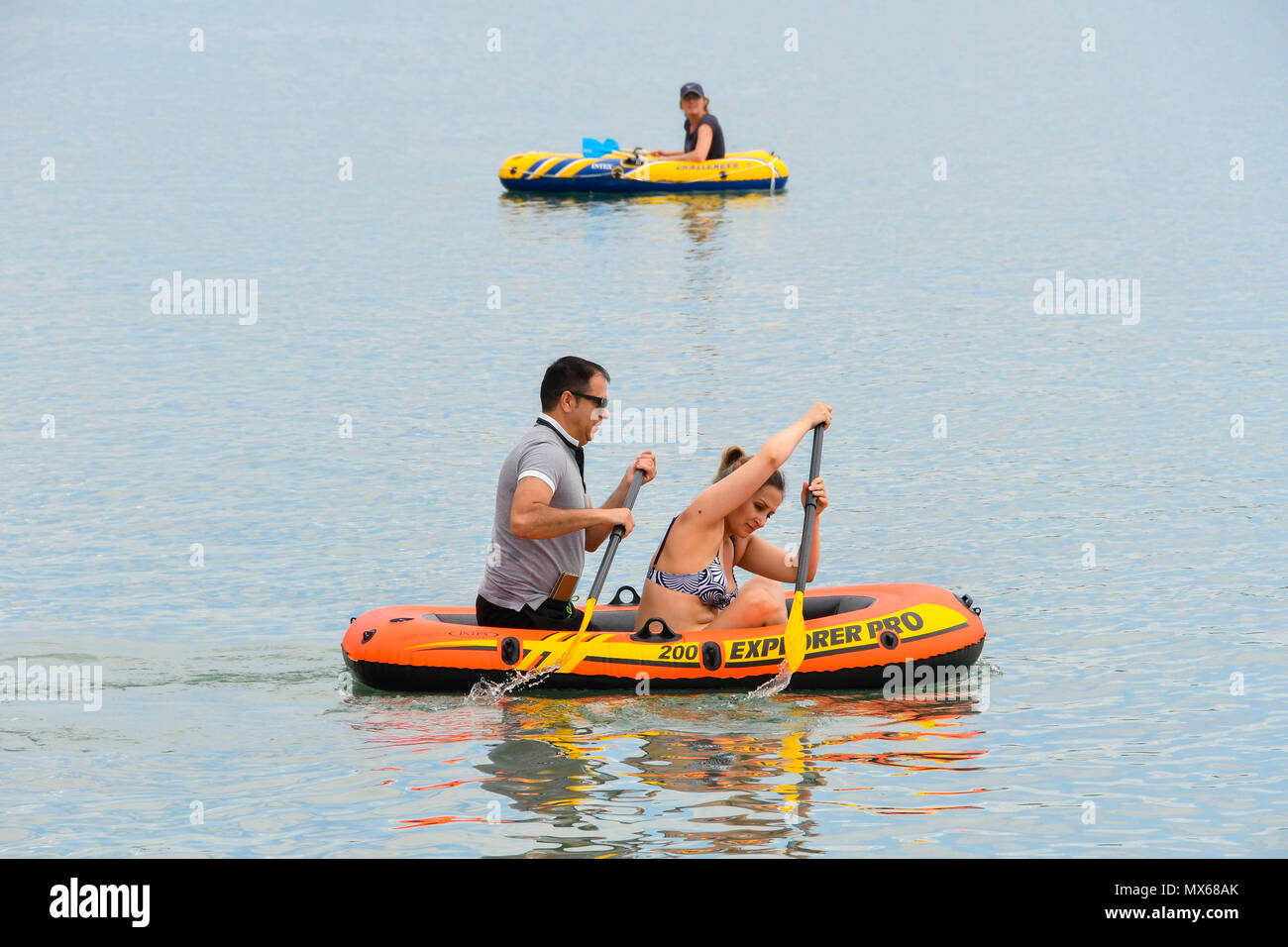 Lyme Regis, Dorset, UK.  3rd June 2018. UK Weather.  Holidaymakers and visitors flock to the beach at the seaside resort of Lyme Regis in Dorset to enjoy the warm hazy sunshine on the last day of the school half term holidays.  I think we need a bigger boat!  Two adults in a small inflatable boat.  Picture Credit: Graham Hunt/Alamy Live News Stock Photo