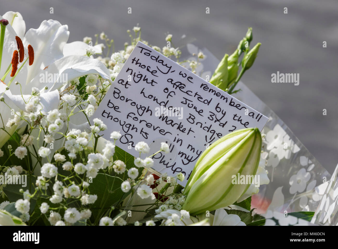 London Bridge, Southwark, London, 3rd June 2018. Flowers are laid at the site, and members of the public, including families of victims, pay their respects. Some hold placards with messages. Following a service at Southwark Cathedral commemorating the first anniversary of the London Bridge terror attack, those who died or were harmed in the attack are remembered by a procession, flower laying and a minute’s silence at London Bridge in Southwark.. Credit: Imageplotter News and Sports/Alamy Live News Stock Photo