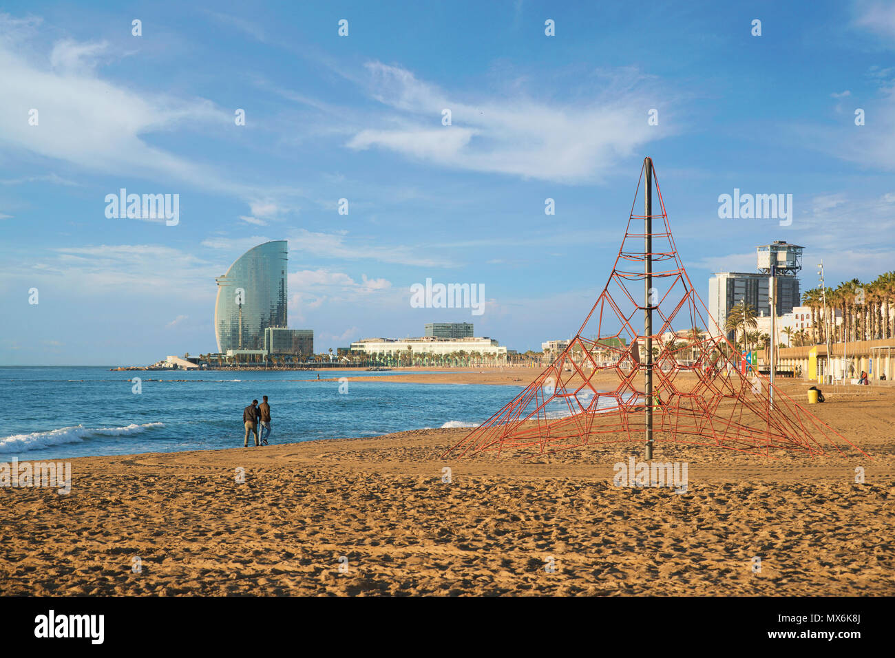 Pedestrians walk along Barceloneta Beach in Barcelona with colorful sky at sunrise. Seafront, beach,coast in Spain. Suburb of Barcelona, Catalonia Stock Photo