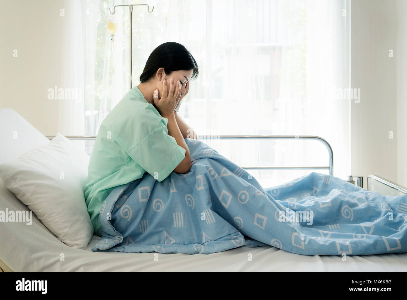Asian young woman patient lying at hospital bed feeling sad and depressed worry. Disease feeling sick in health care and clinical attention concept. Stock Photo
