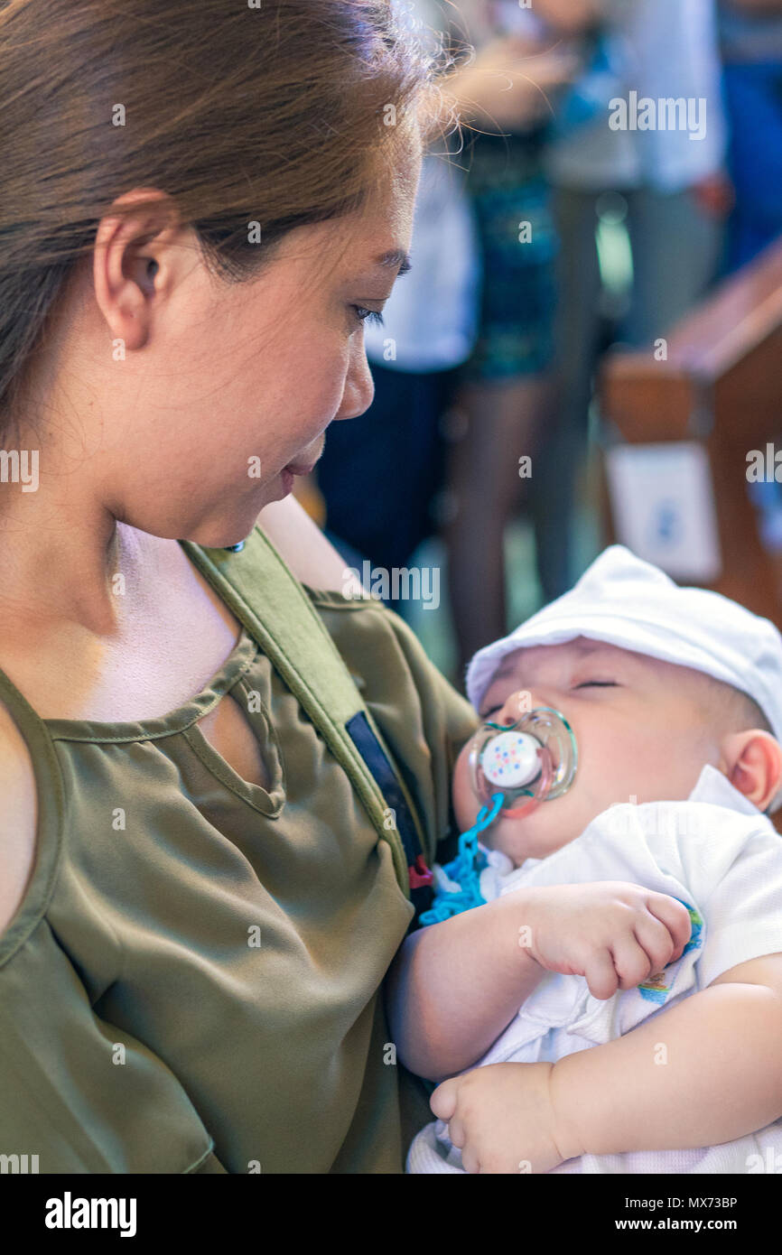 Mother holds sleeping new born baby boy during baptism ceremony Stock Photo Alamy