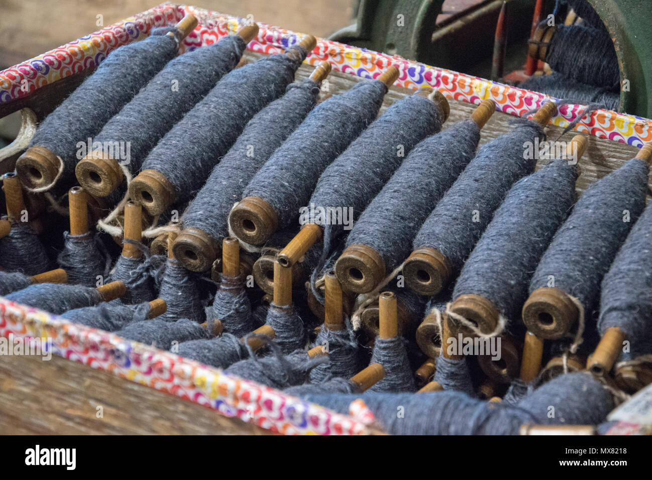 Box of bobbins with navy blue strands of yarn. Custom Woolen Mills, Carstairs, Alberta Stock Photo