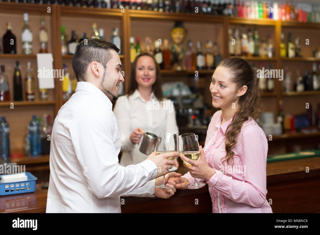 Happy couple sitting at bar and female bartender pouring coffee Stock Photo