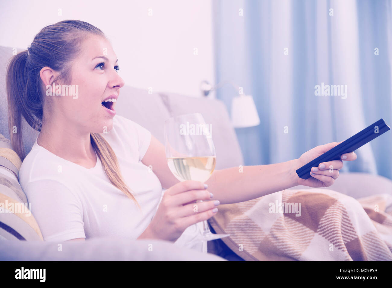Girl is resting with wine and watching TV at home Stock Photo - Alamy