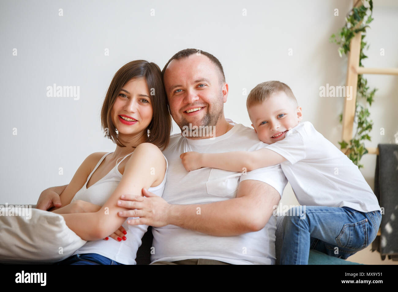 Photo of cuddling parents with son sitting on sofa in room Stock Photo ...