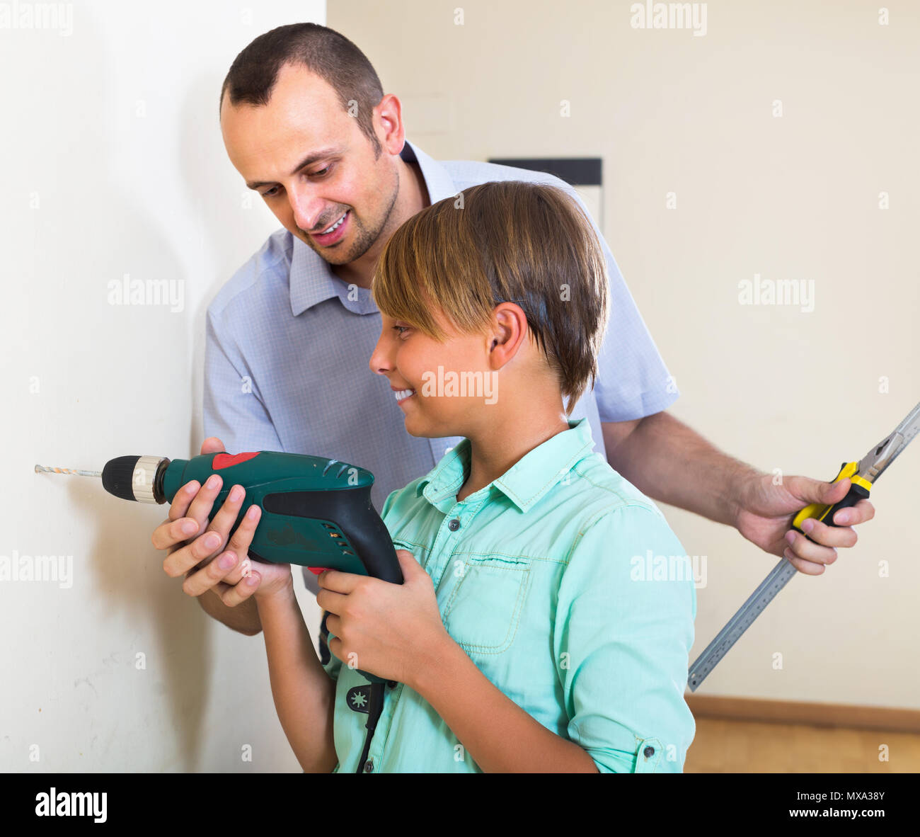 Positive man teaching happy son to using electric drill Stock Photo