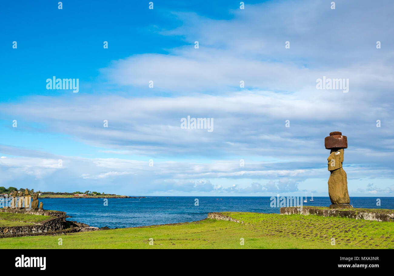 Ahu Ko Te Riku with restored obsidian eyes and Ahu Vai Ure, Tahai complex, Hanga Roa, Easter Island, Rapa Nui, Chile, and sailboats in Pacific Ocean Stock Photo