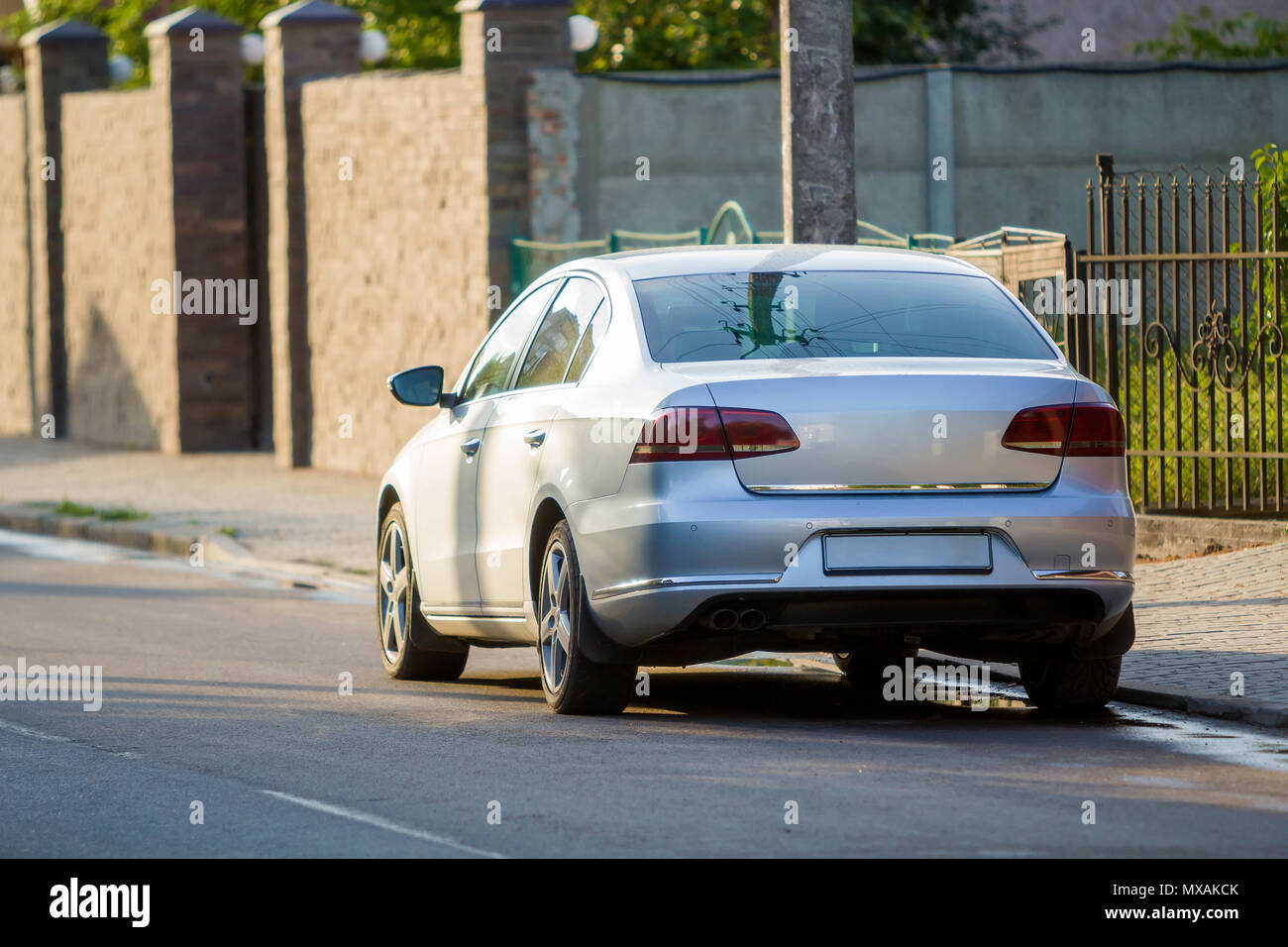 Closeup back view of new shiny expensive silver car moving along city