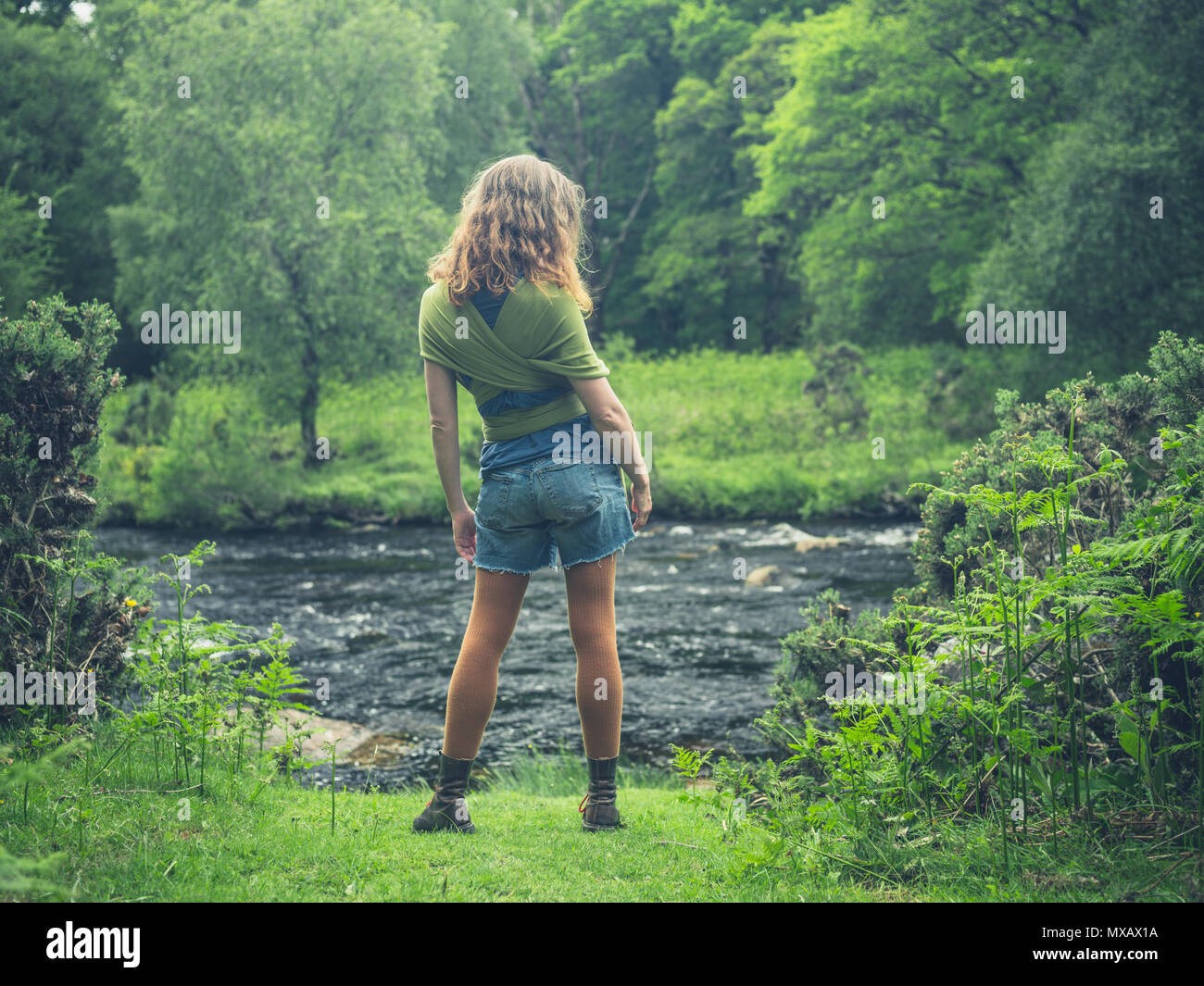 A young woman is standing by a river in nature Stock Photo - Alamy
