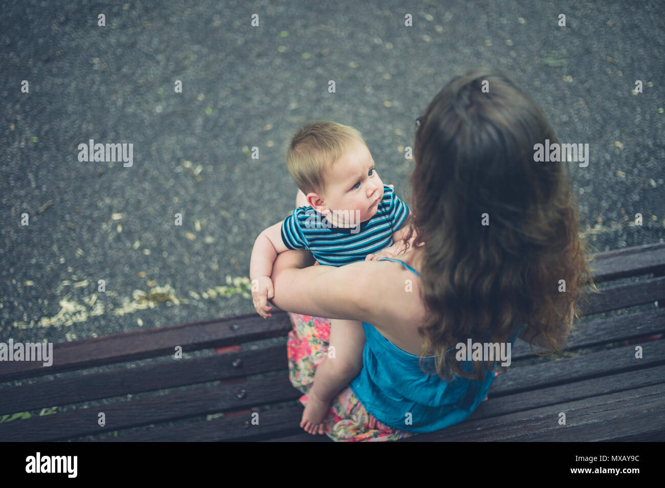 A young mother is sitting on a park bench with her baby Stock Photo - Alamy