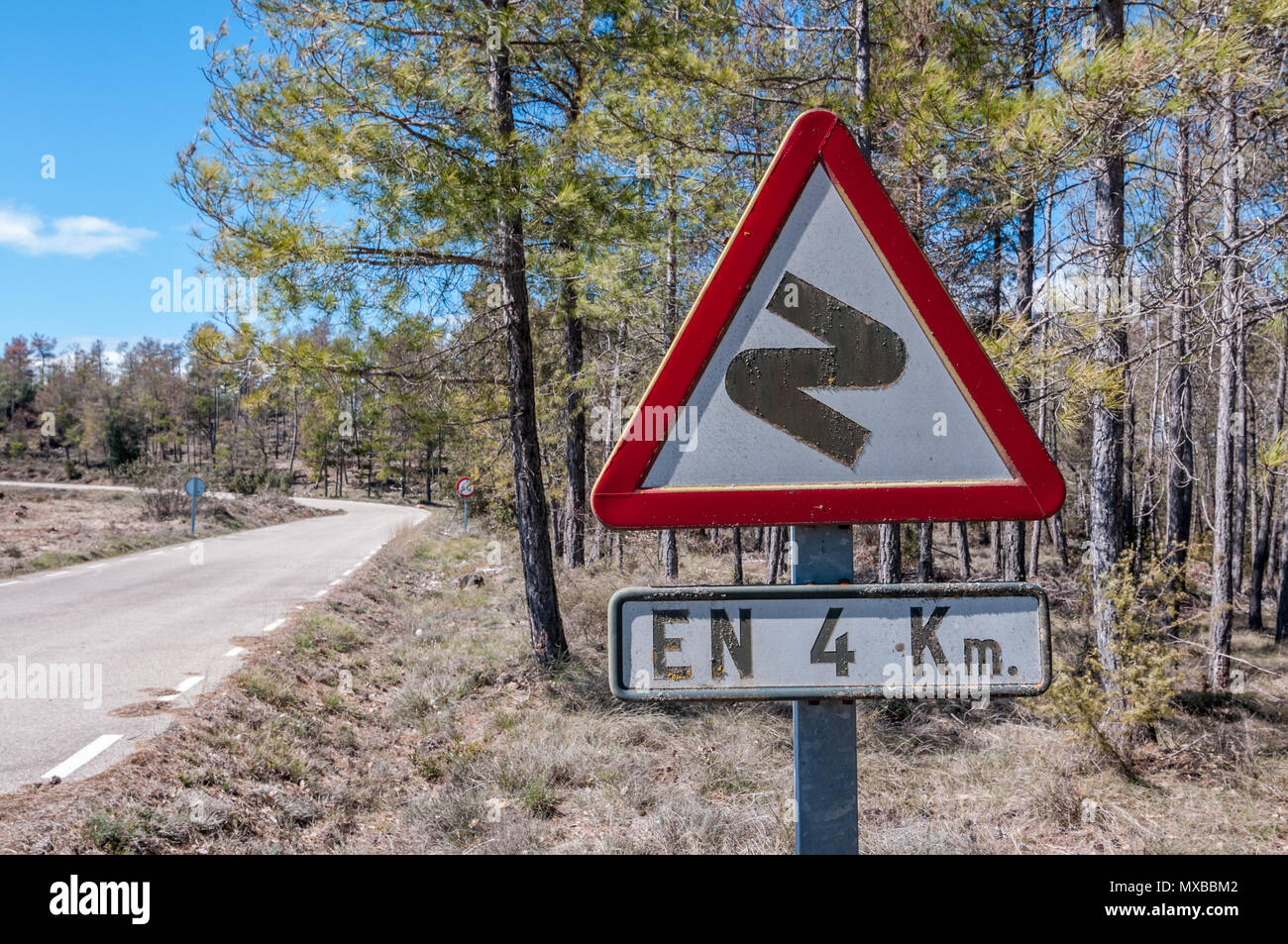 Dangerous curves ahead, first to right, in 4 Km, spanish traffic sign, country side road, Spain Stock Photo