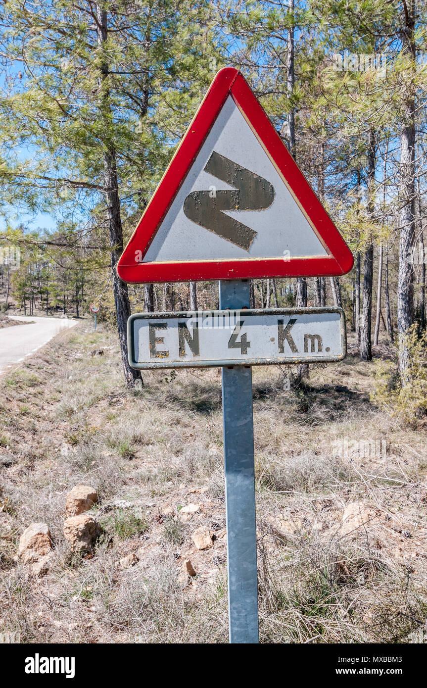 Dangerous curves ahead, first to right, in 4 Km, spanish traffic sign, country side road, Spain Stock Photo