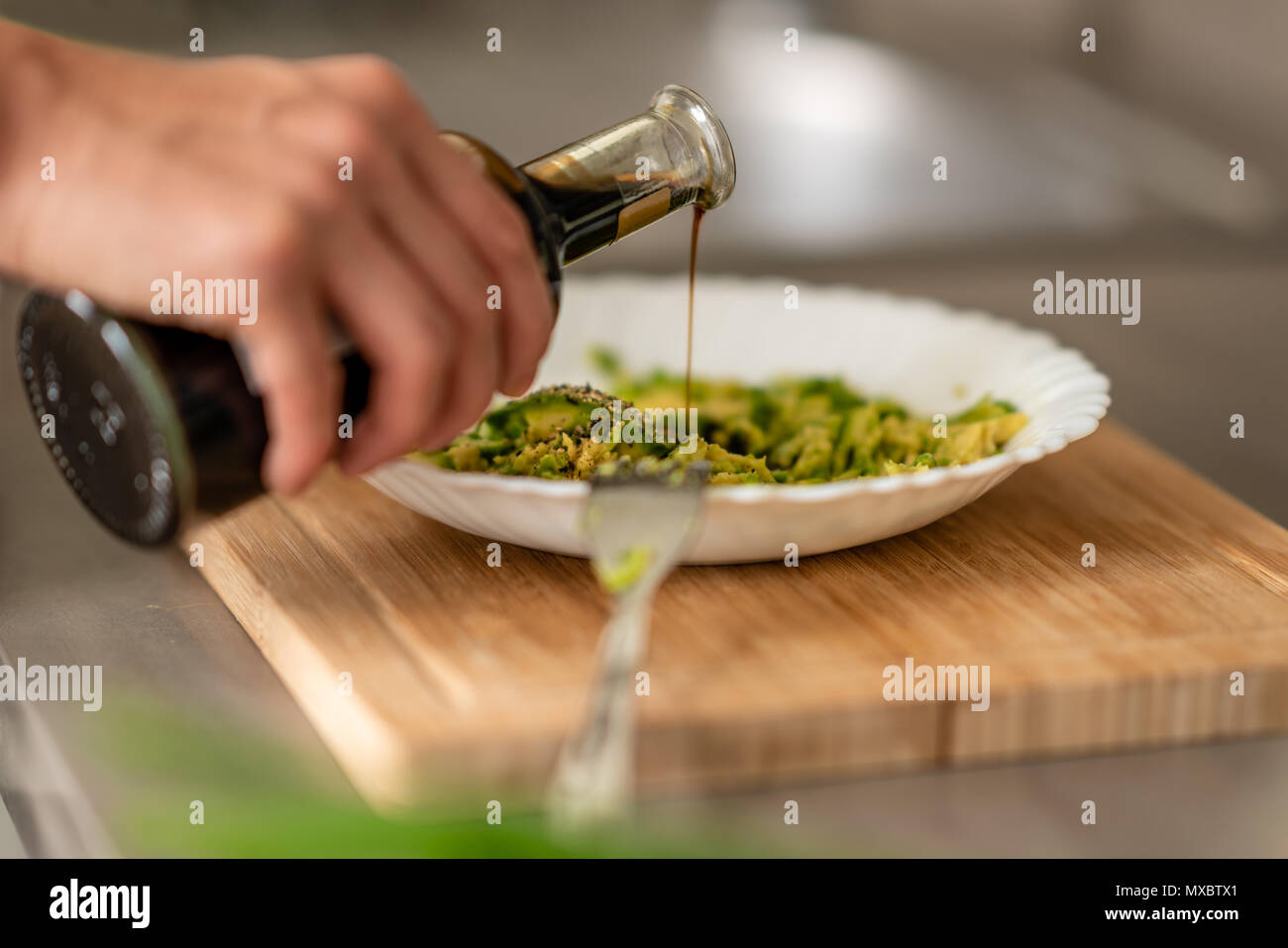 A woman is spicing up the Guacamole with Balsamico. Stock Photo