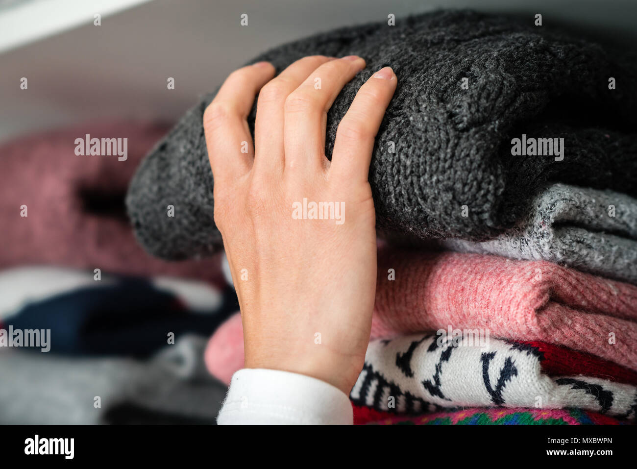 Woman is getting out the winter cloth out of the wardrobe. Stock Photo