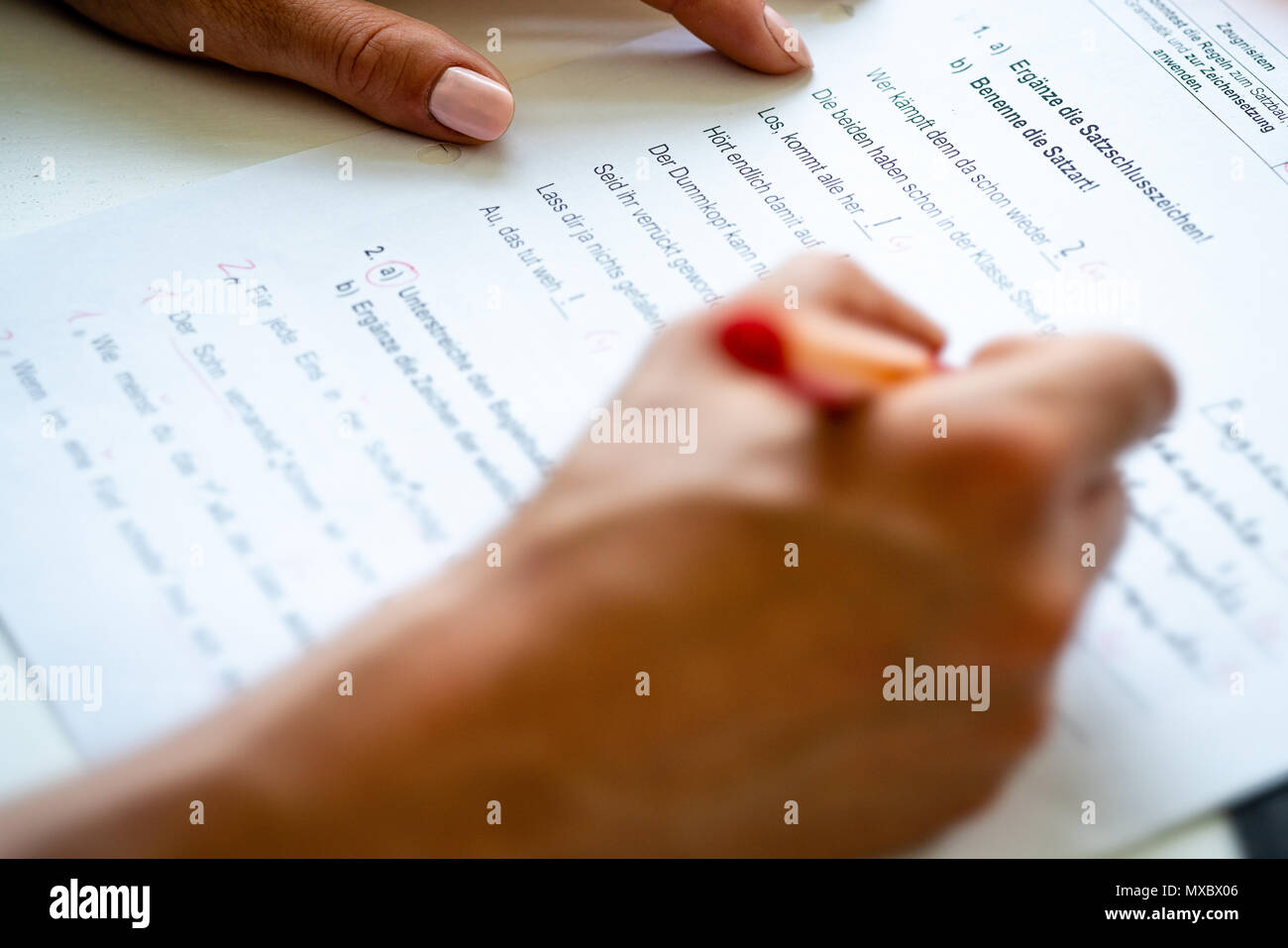 A woman is correcting a test in german language. Stock Photo