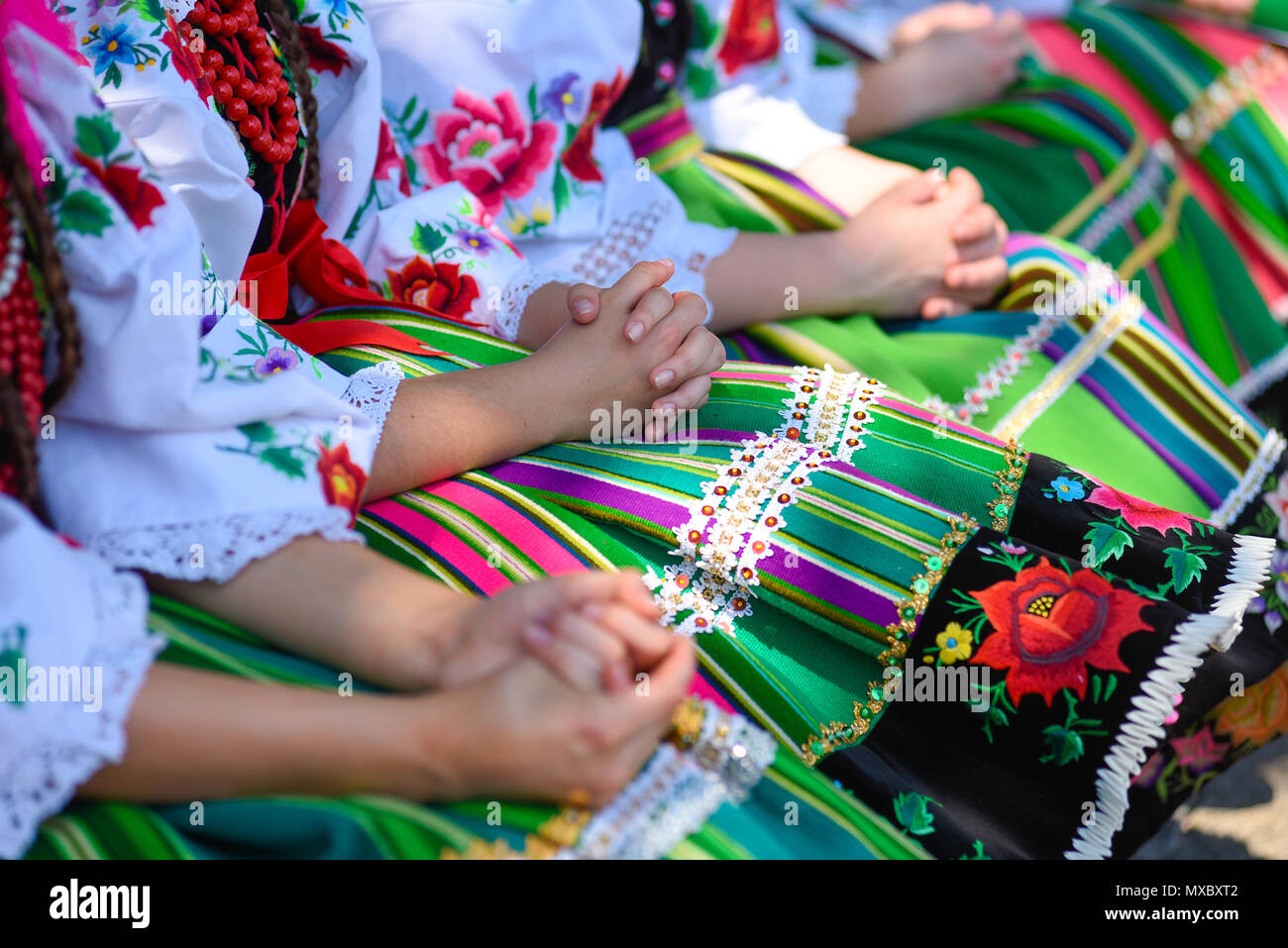 Regional, folklore costumes, colorful handmade skirts with stripes and symbols embroidered. During Corpus Christi parade. Stock Photo