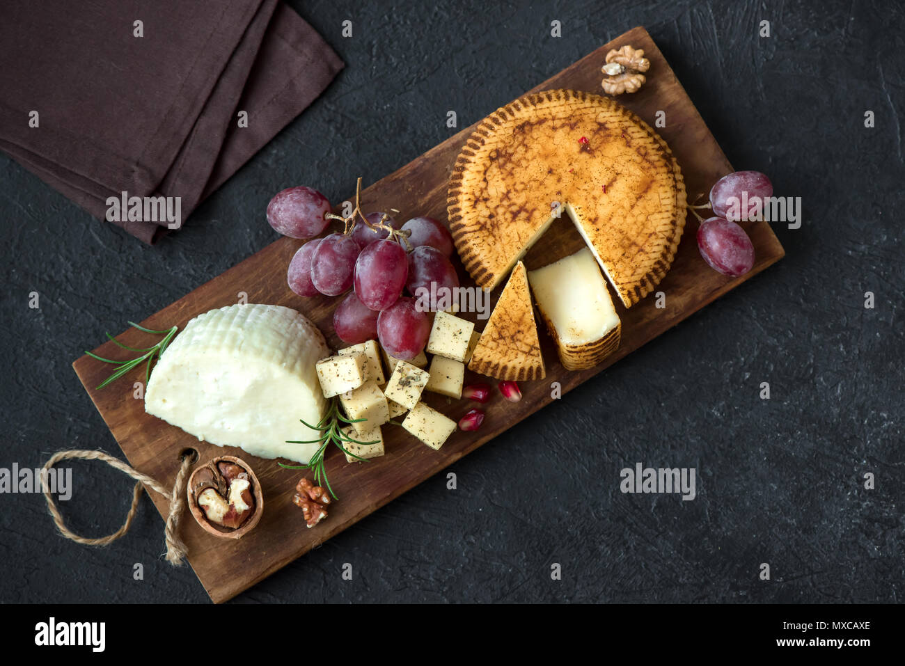 Cheese platter with assorted cheeses, grapes, nuts over black