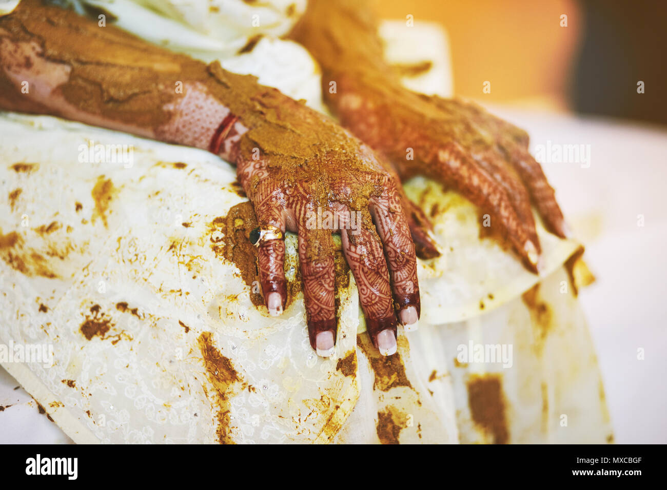 Focus on the bride's hand with mehndi (henna tattoo art) and turmeric (haldi) oil pasted, one of the traditional rituals indian marriage ceremony Stock Photo