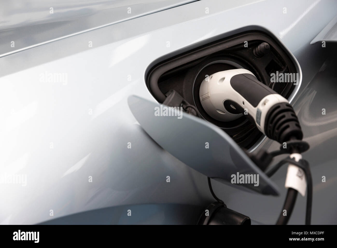 Electric car charger plugged in an electric vehicle. Stock Photo