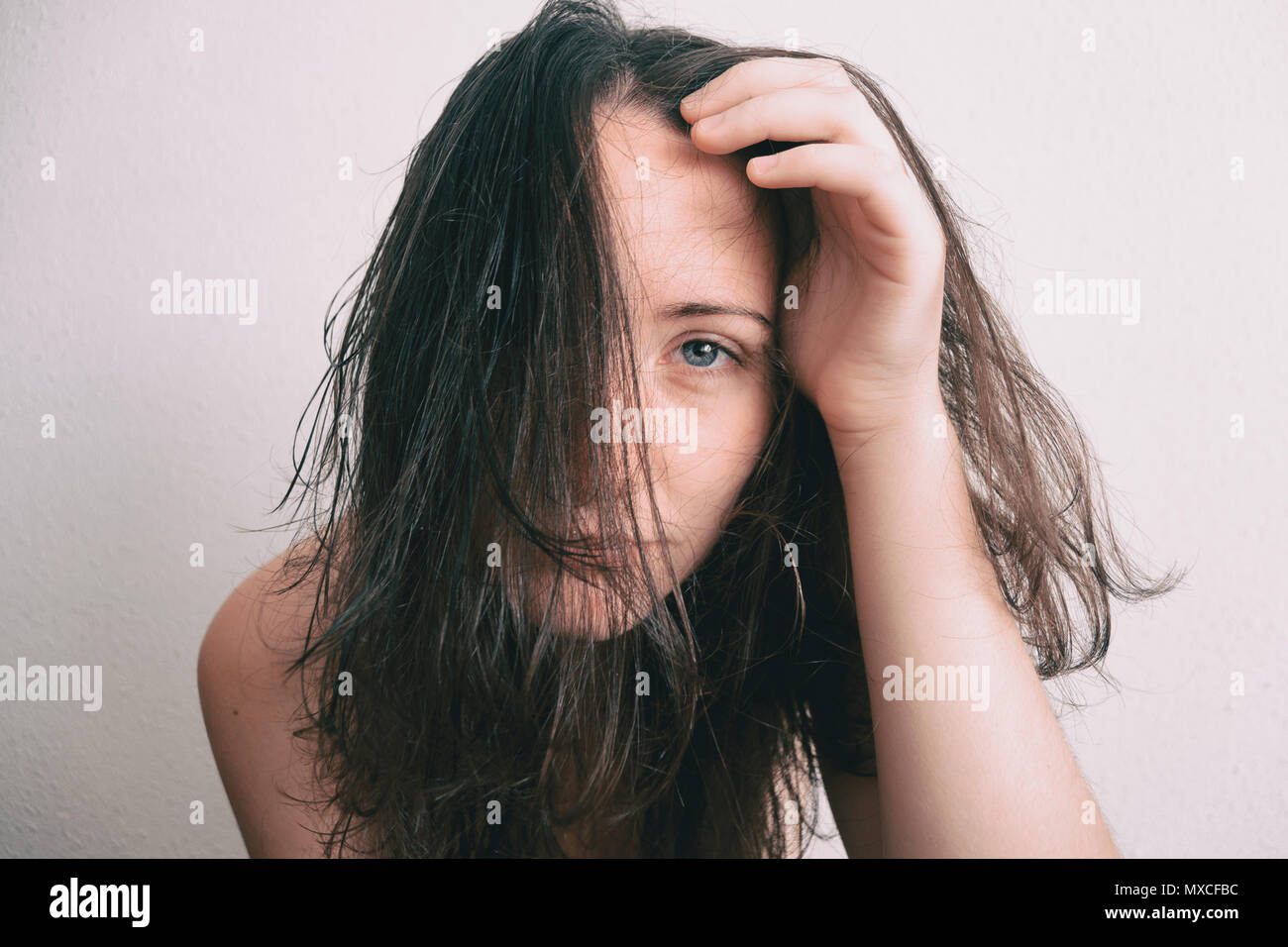 a girl with her face full of hair removing it with her hand Stock Photo