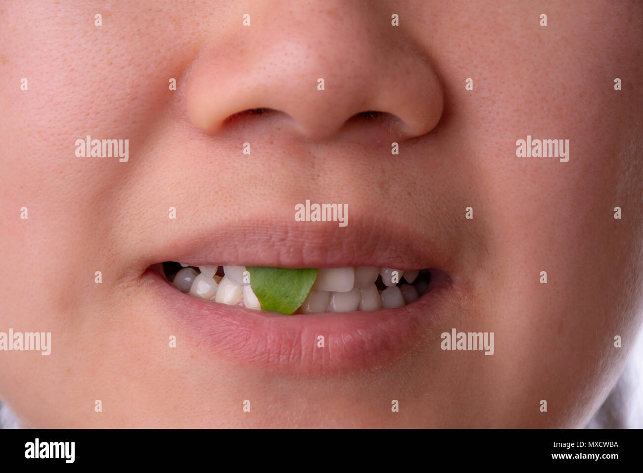 Close-up of woman smiling with spinach or salad stuck in her teeth Stock Photo