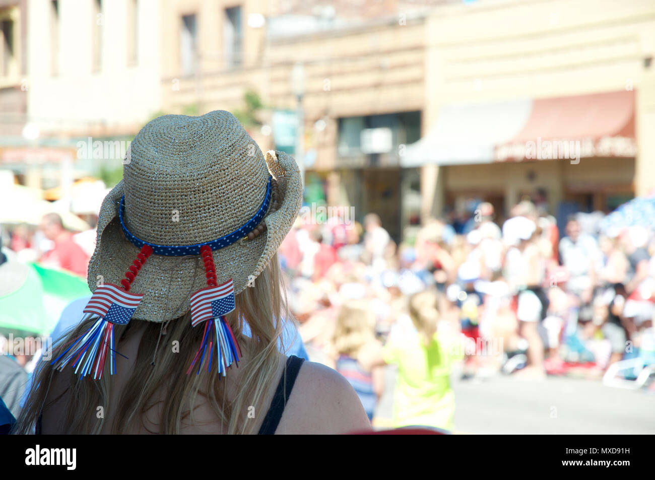 Back of woman in straw hat at July 4th celebration with small American flags in her hat Stock Photo