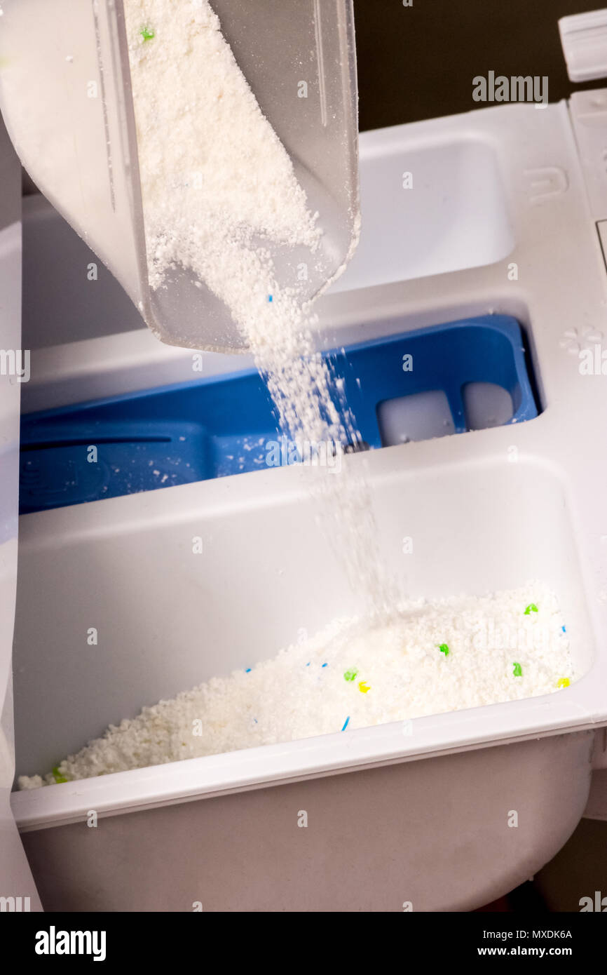 woman is pouring powder detergent in wash machine to washing dirty
