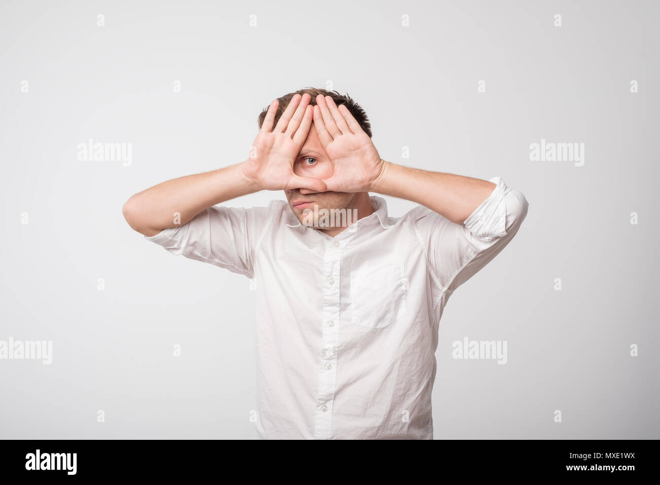 Young caucasian man hiding his face with hand Stock Photo