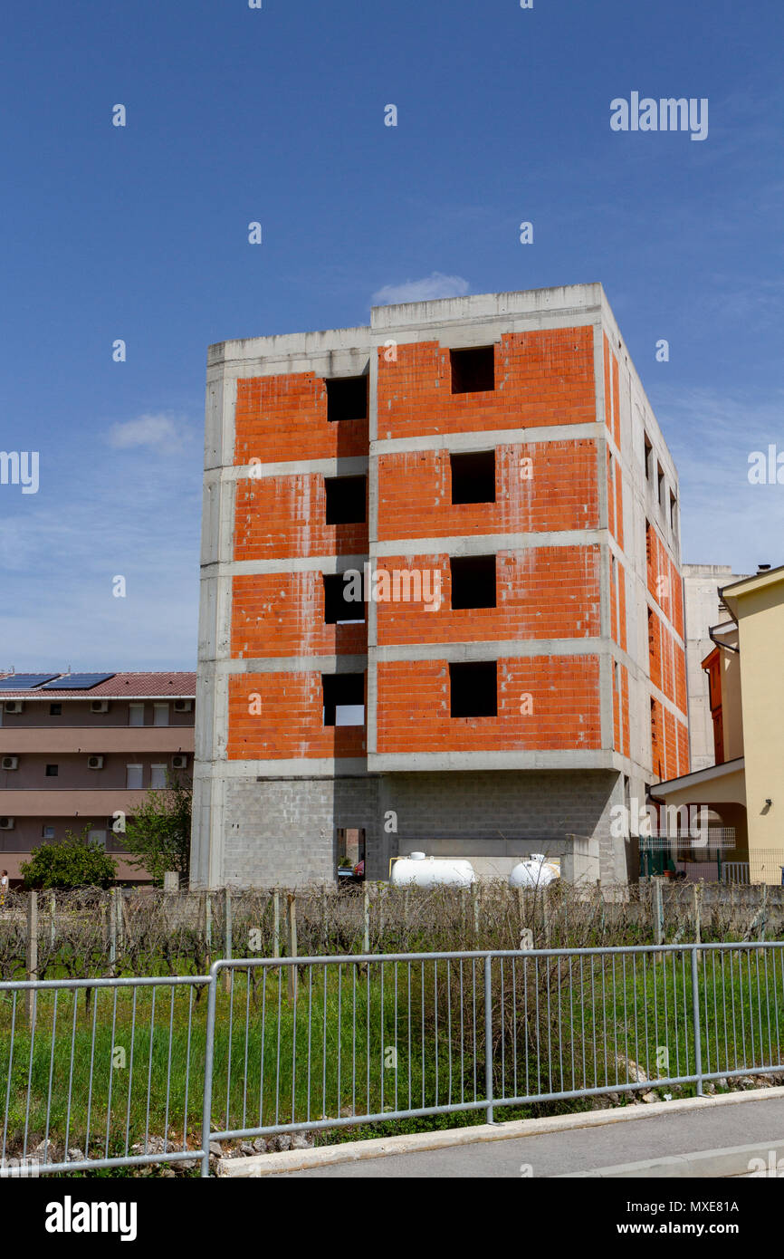 Tower block during construction showing exposed brickwork and concrete frame in Međugorje (or Medjugorje), Federation of Bosnia and Herzegovina. Stock Photo