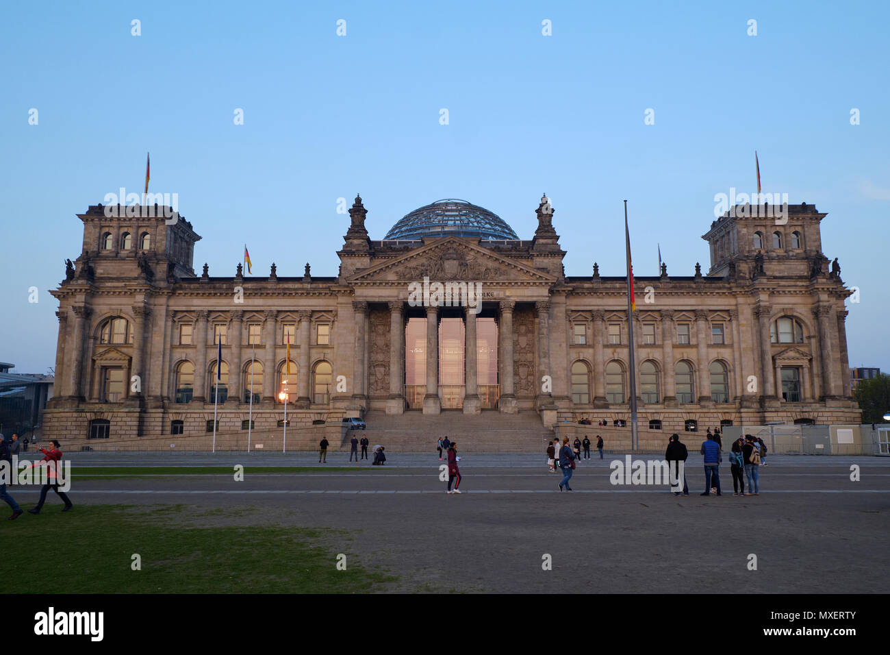 Berlin, Germany - April 14, 2018: Front view of Reichstag building with walking tourists on the foreground at sunset Stock Photo