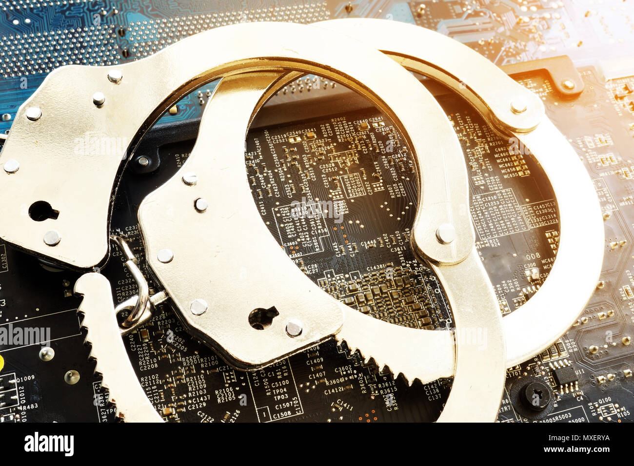 Handcuffs and electronic devices. Cyber crime or fraud. Stock Photo