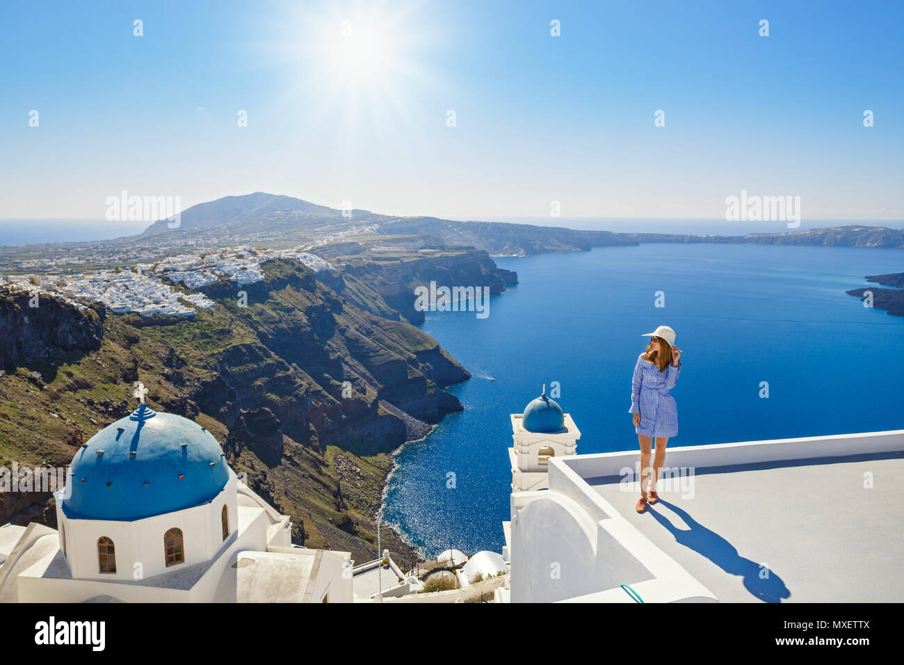 Young woman stands on a hill and looks at the marine landscape of Santorini, Greece Stock Photo