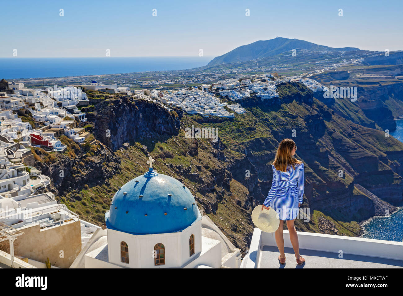 Young woman stands on a hill and looks at the marine landscape of Santorini, Greece Stock Photo