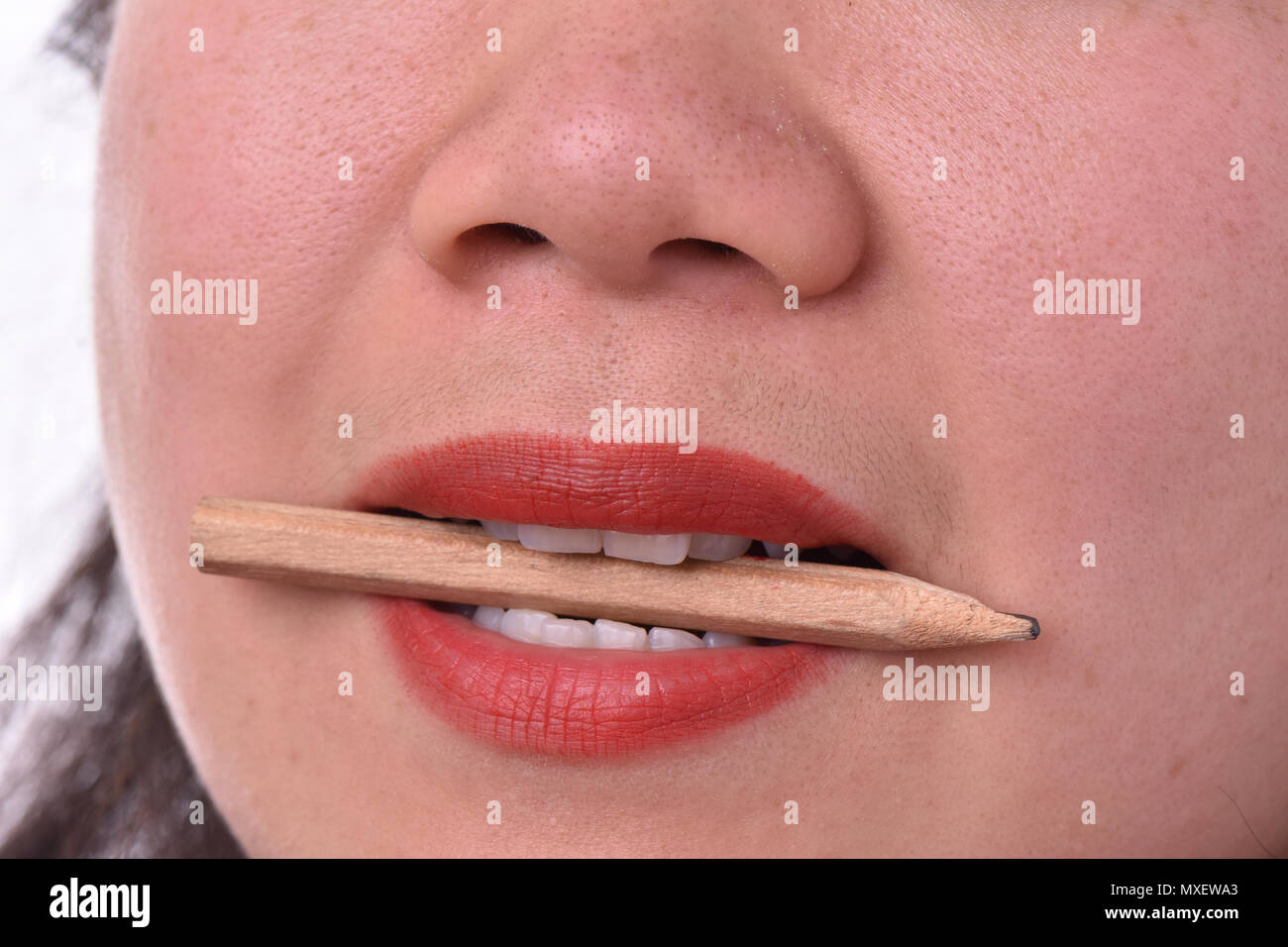 Close-up of woman with red lipstick bitting pencil Stock Photo