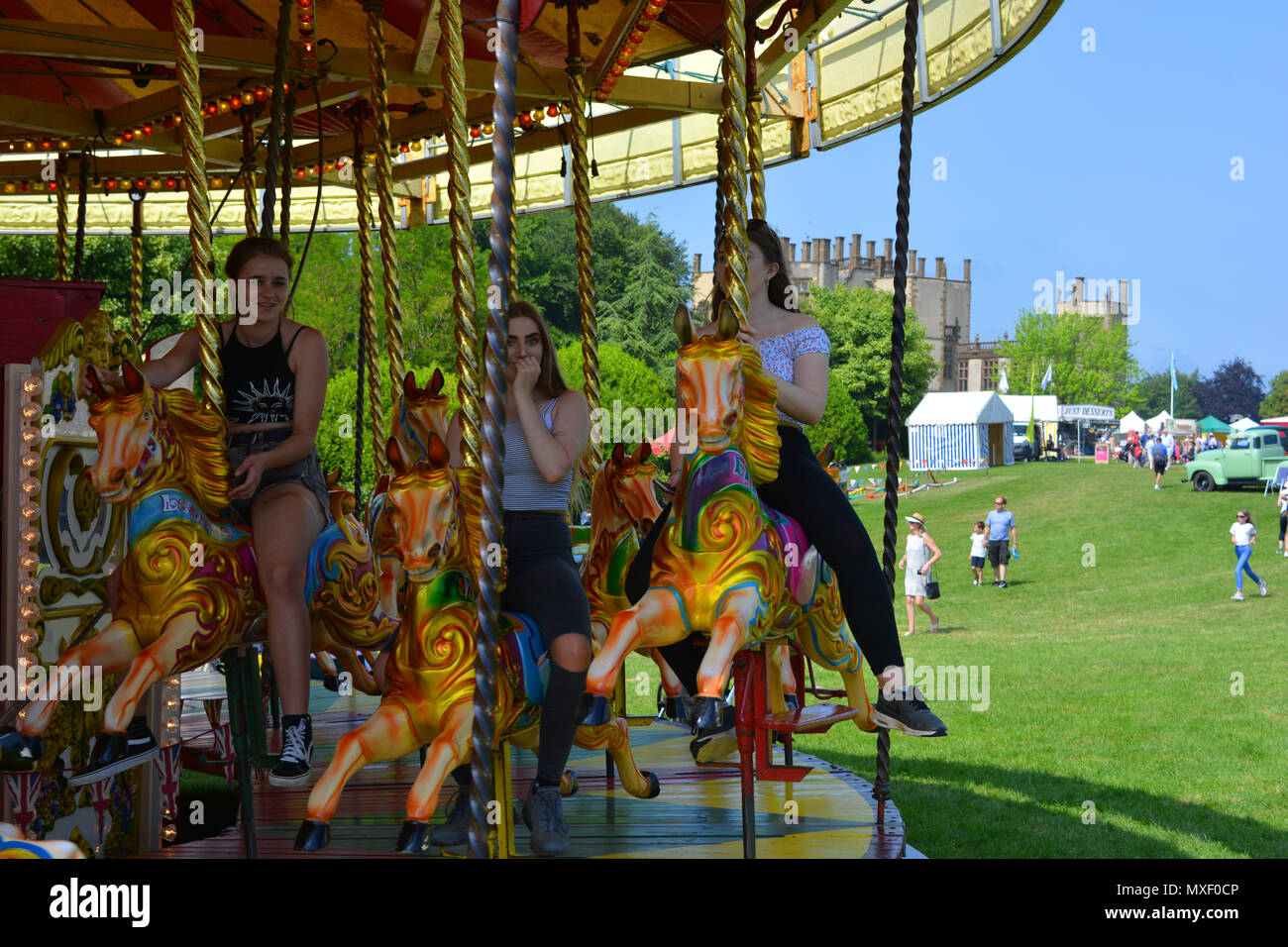 Teenage girls riding horses on a merry-go-round at the annual Sherborne Castle Country Fair, Sherborne, Dorset, England Stock Photo