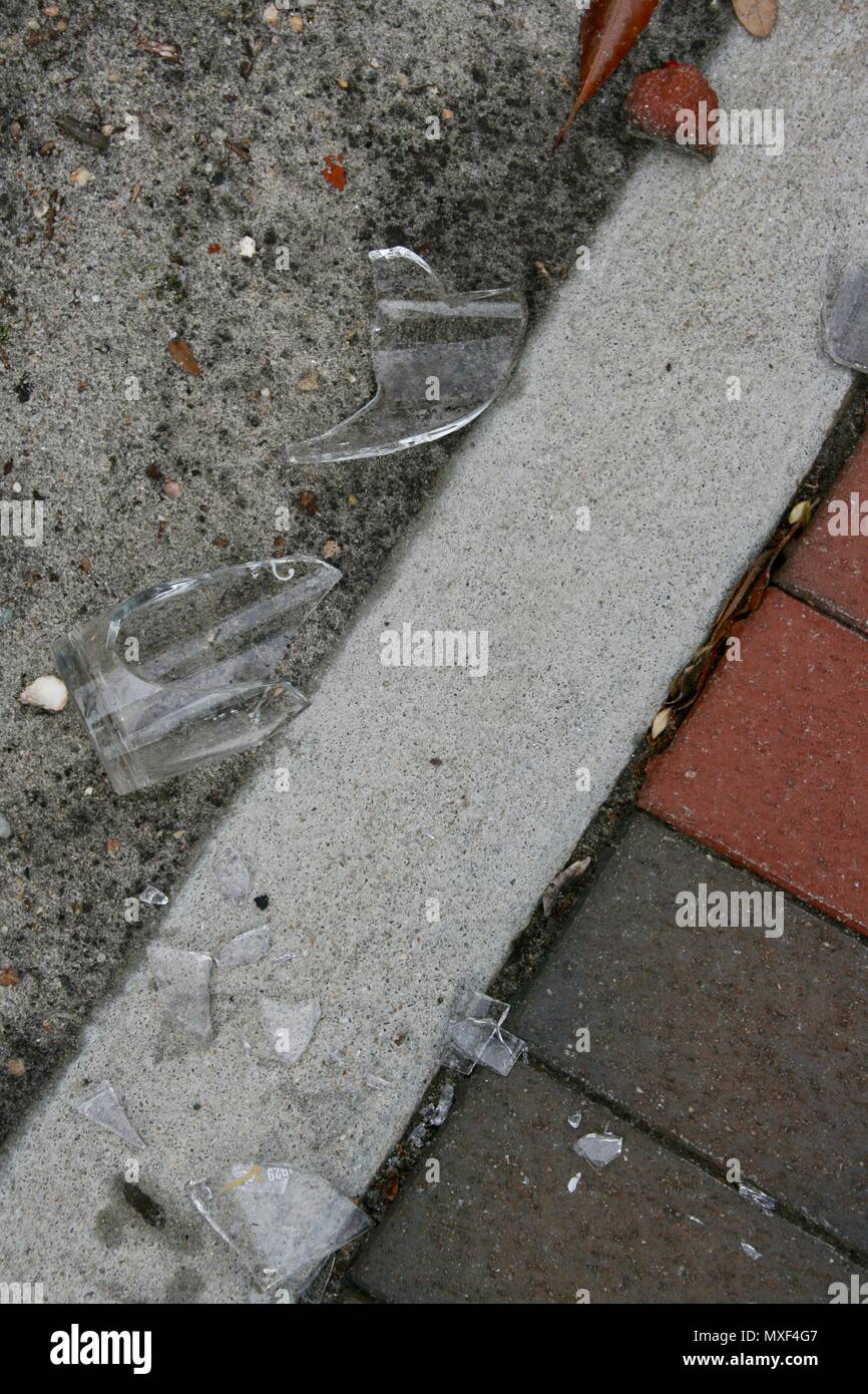 Clear broken glass on sidewalk pavement of brick and cement. Stock Photo