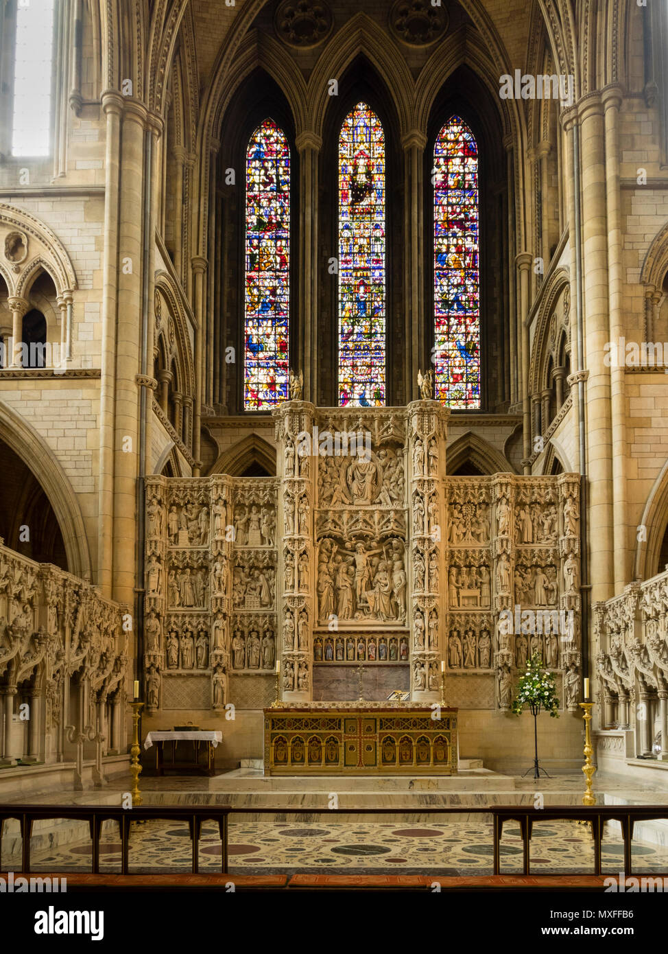 Altar and intricately carved reredos below the stained glass window of