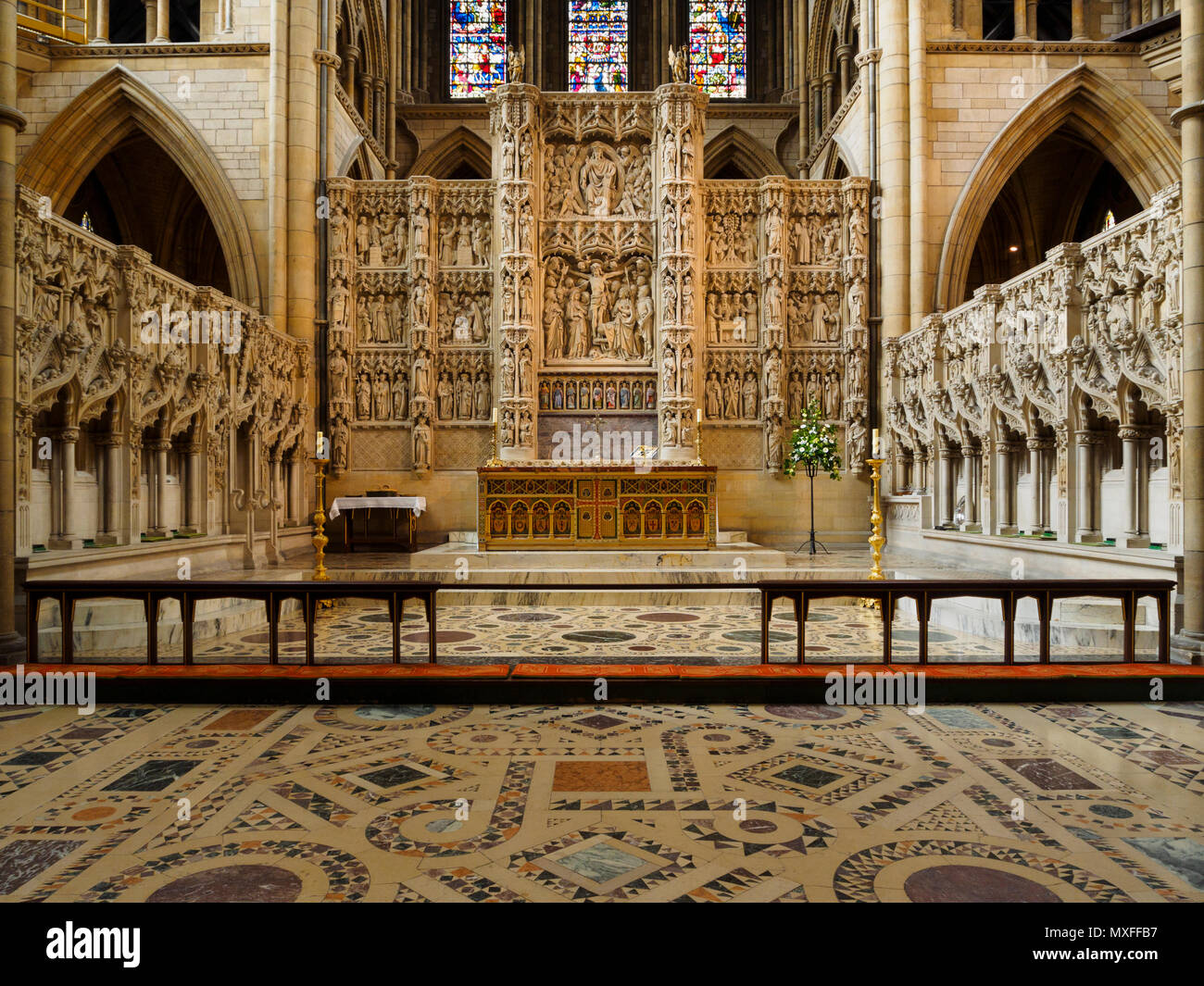 Altar and intricately carved reredos below the stained glass window of the Victorian Truro Cathedral, Cornwall, UK Stock Photo