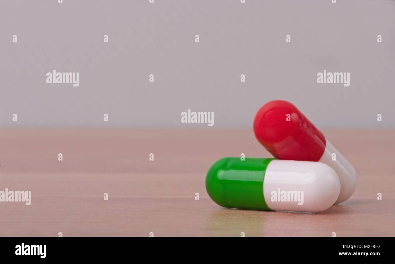 wo medical capsules on a table with grey copy space background. Stock Photo