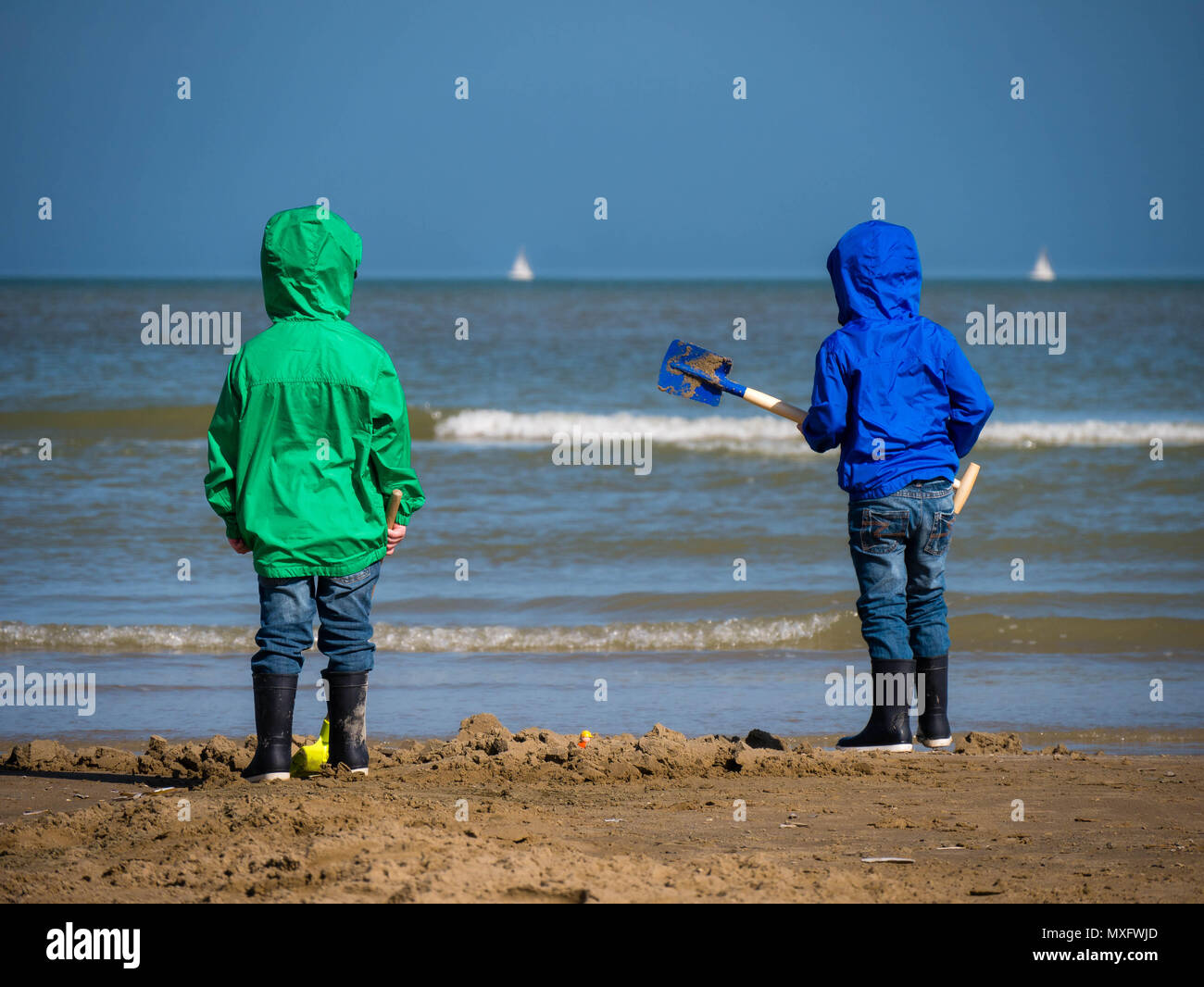 Two boys from behind looking towards the open sea in Bray-Dunes, France Stock Photo