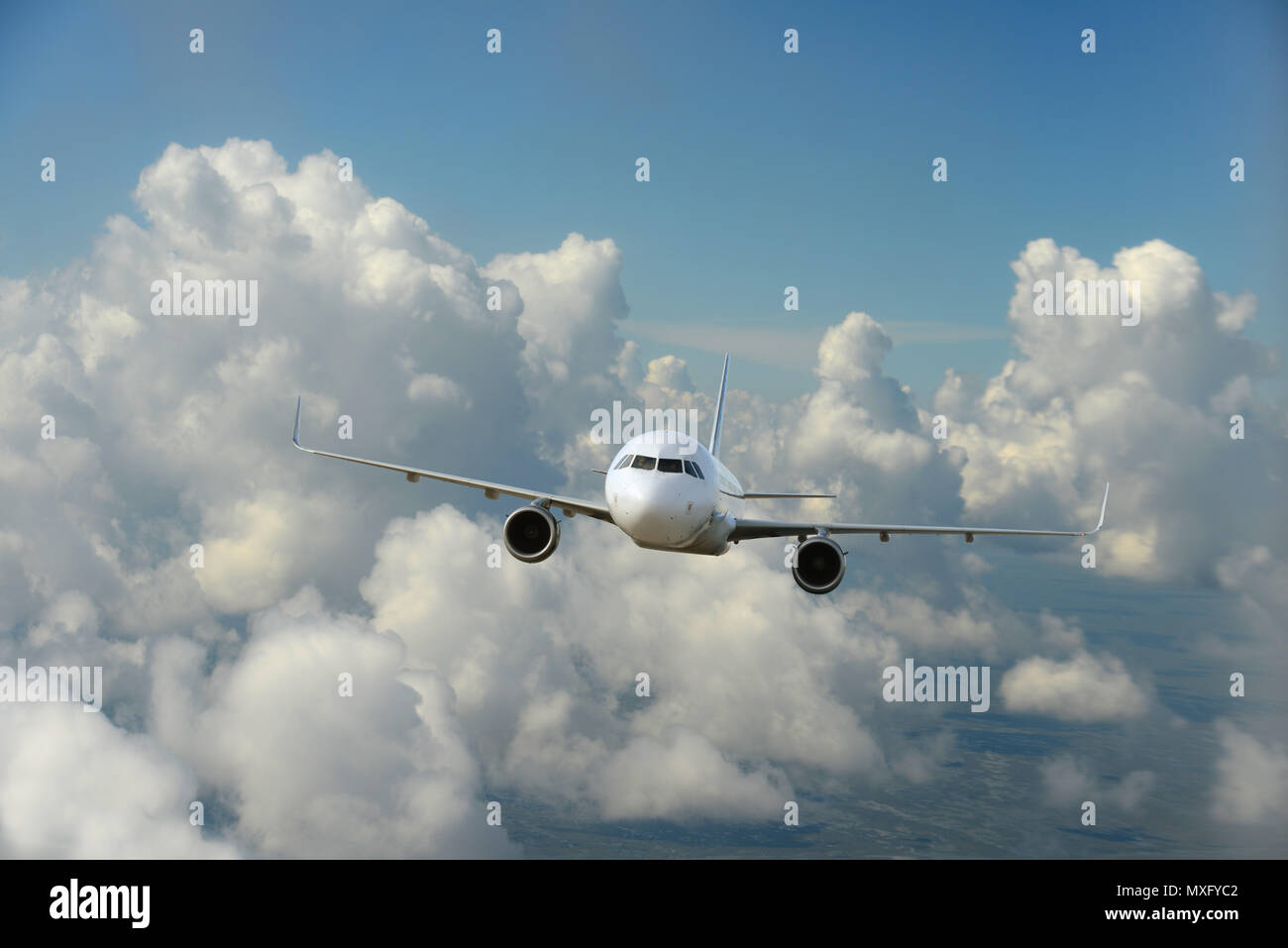 Commercial airplane flying over the clouds and blue skies as background Stock Photo