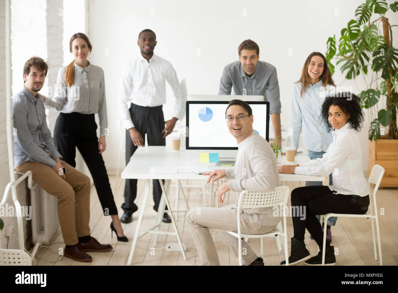 Multiracial team with group leader posing smiling at camera Stock Photo