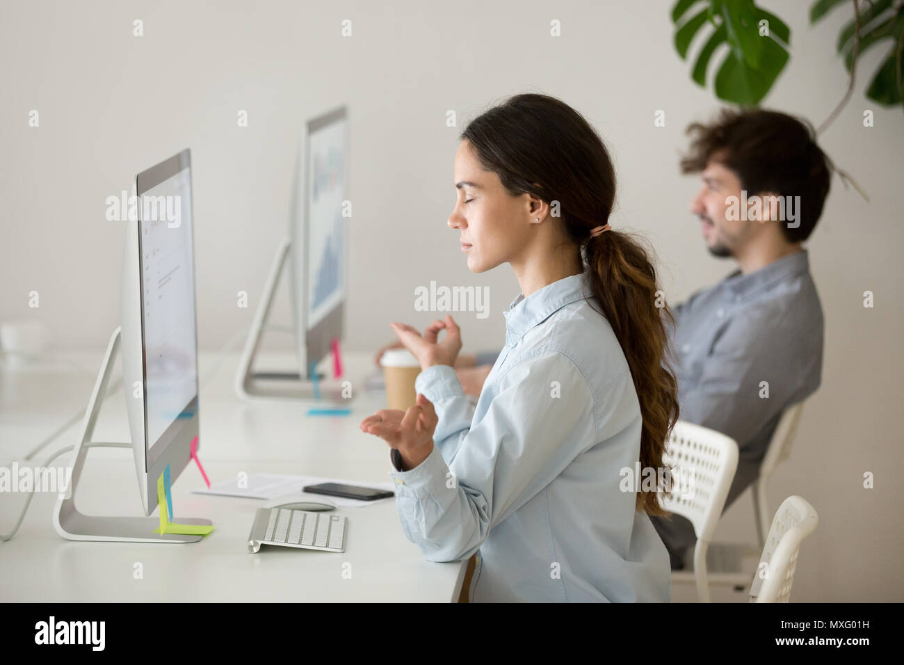Concentrated female employee meditating at workplace Stock Photo