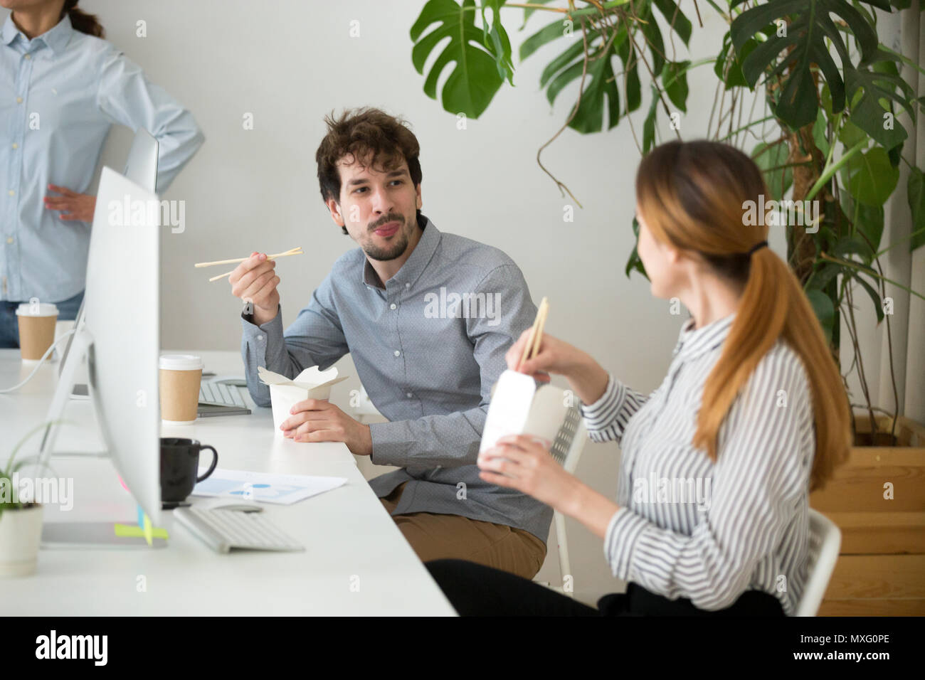 Colleagues eating Asian food from boxes during office lunch brea Stock Photo